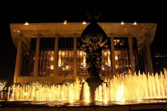 The Dorothy Chandler Pavilion lit at night behind the Music Center plaza fountains
