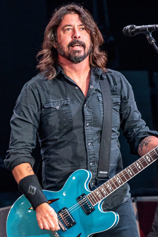 Dave Grohl playing a teal hollow-body guitar on stage