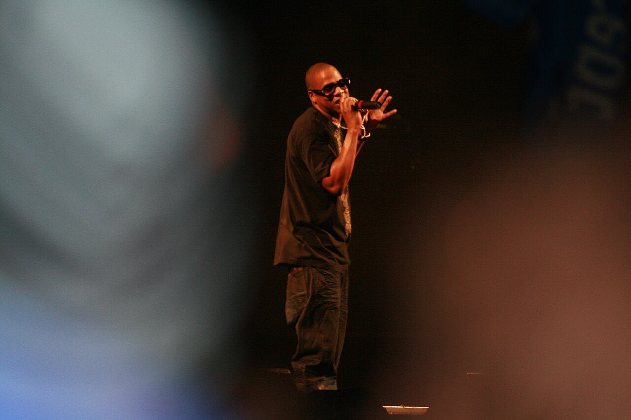 Jay-Z in sunglasses rapping into a microphone on stage at Glastonbury in 2008