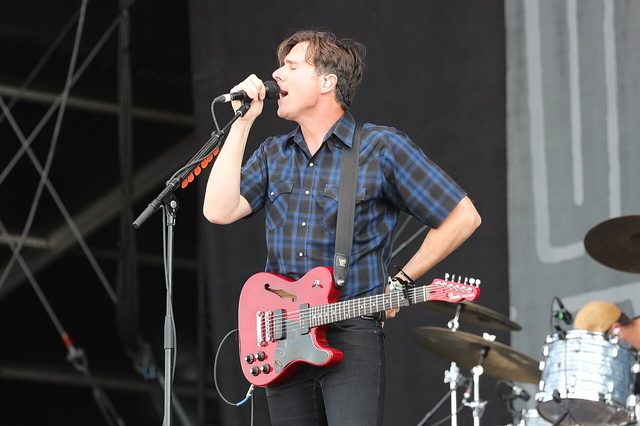 Jim Adkins of Jimmy Eat World singing with a red electric guitar at a festival