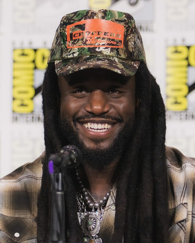 Shaboozey smiling in a camouflage cap at San Diego Comic-Con in 2026
