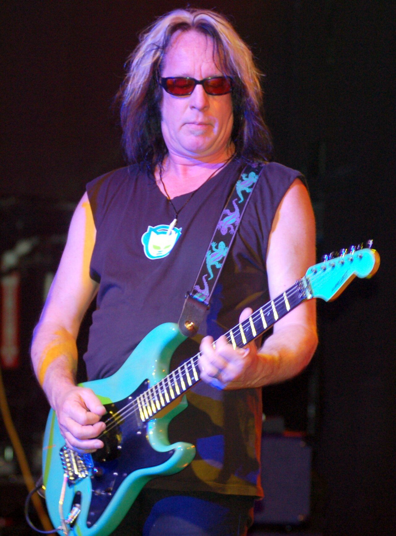 Todd Rundgren playing a teal electric guitar on stage in 2009