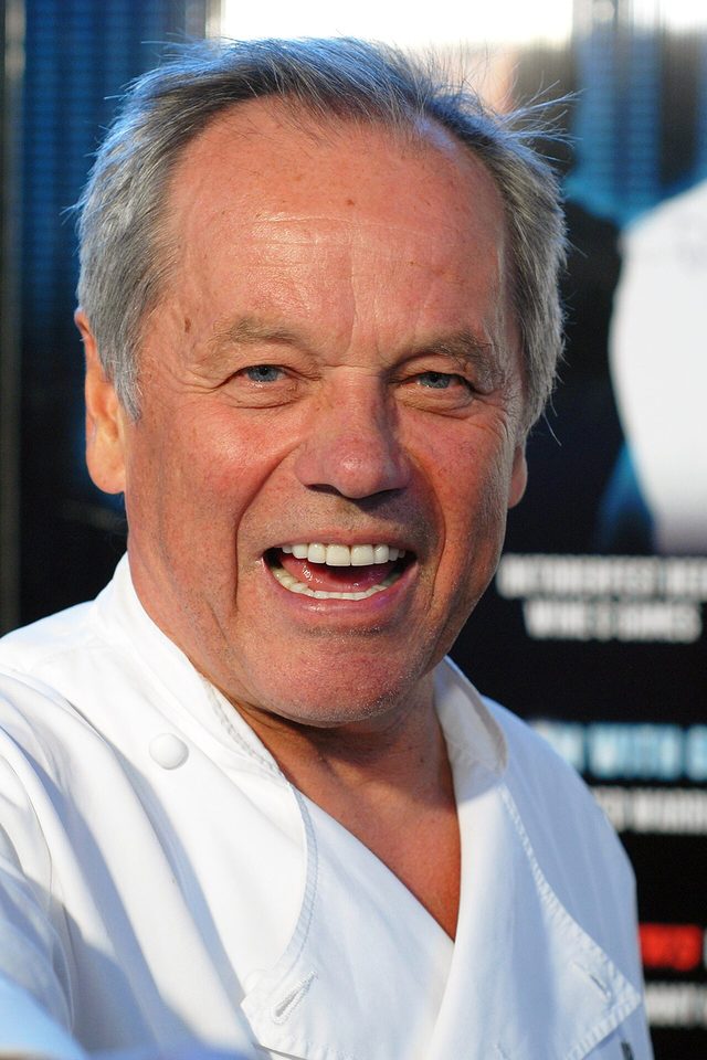 Wolfgang Puck laughing in a white chef’s jacket at an event in Los Angeles in 2012